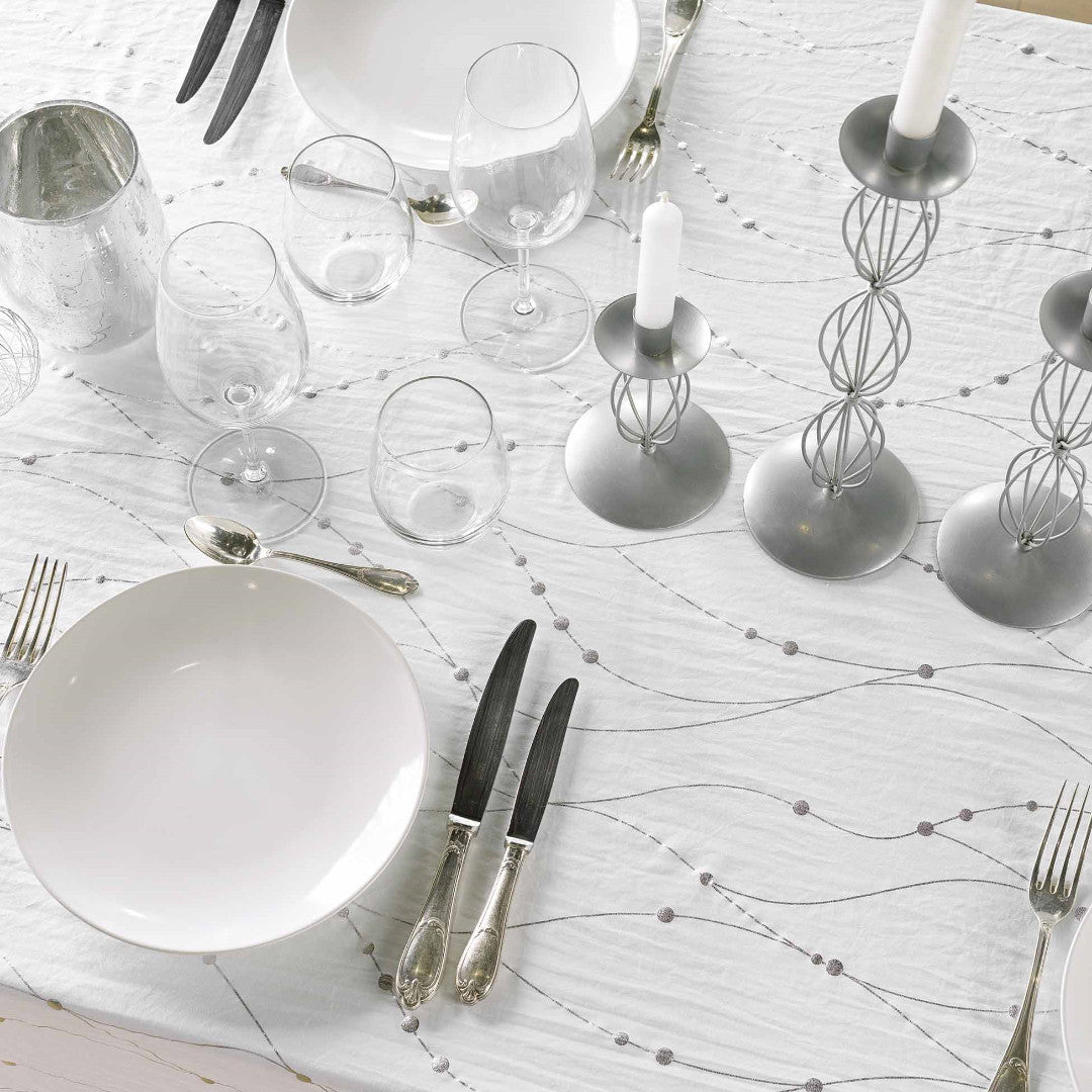 Nahaufnahme einer Tischdekoration mit Firmament Metallic weißer Tischdecke mit wellenförmigem Silberprint