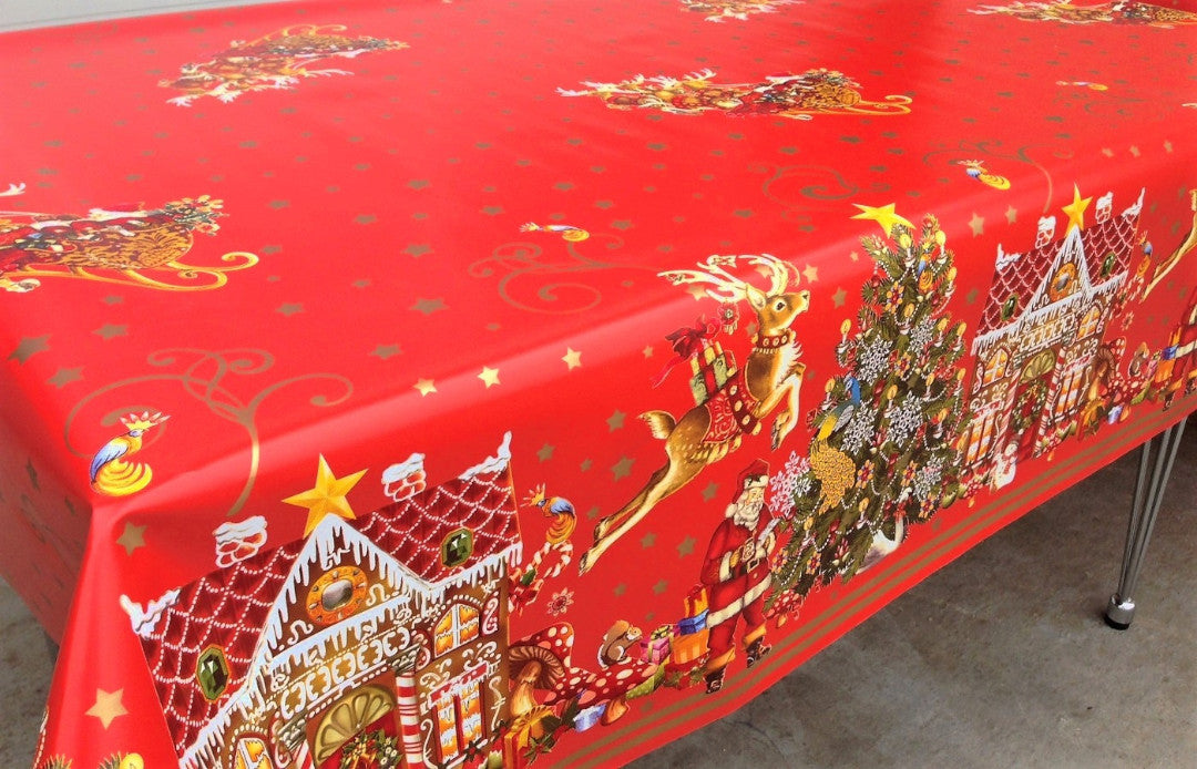 Jul i Kagehuset Wachstuch Tischdecke auf dem Esstisch mit Weihnachtsmotiven wie Tannenbäumen und Lebkuchenhäusern