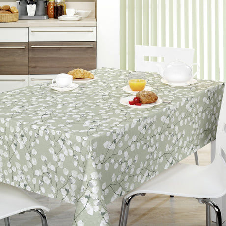 Nova Green Wachstuch Tischdecke auf einem Tisch mit hellgrünem Hintergrund und weißen Blättern